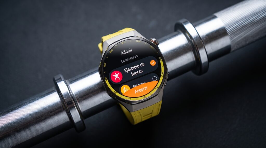Smartwatch HUAWEI WATCH GT 7 Pro con correa amarilla apoyado sobre barra olímpica, mostrando el modo de entrenamiento Ejercicio de Fuerza en pantalla.