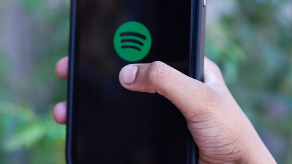 Spotify exige un código QR en el plan Familia: qué pasa si no lo escaneas en 7 días Mano sostiene un celular con el logo de Spotify en la pantalla