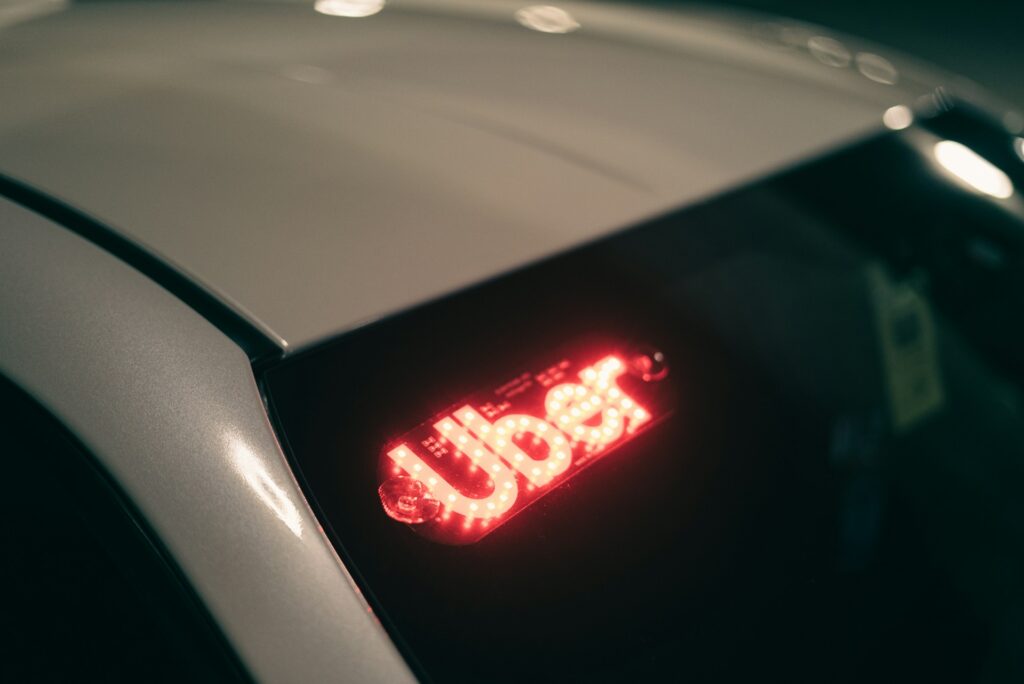 Letrero luminoso con el logo de Uber iluminado en el parabrisas de un vehículo.